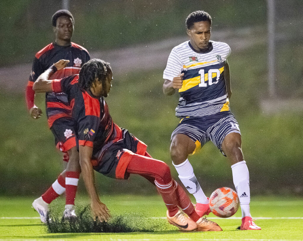 Middleham United FC player Marcelus Bonney trying to avoid a tackle from a Pointe Michel FC player
